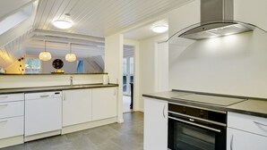 A modern kitchen with white cabinetry, a stainless steel range hood, and a built-in oven. - "Ingalil" - 650m from the sea by Interhome (Væggerløse)