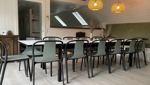 A dining area with a long table and chairs, a ceiling light fixture, and a view of the kitchen through an open door. - "Ingalil" - 650m from the sea by Interhome (Væggerløse)