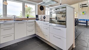 Une cuisine moderne avec des meubles blancs, un four encastré et une machine à café.