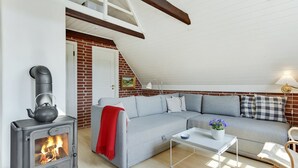 A cozy loft-style living room with a fireplace, a sectional sofa, and a dining area. - "Dordi" - 300m from the sea by Interhome (Fanø)