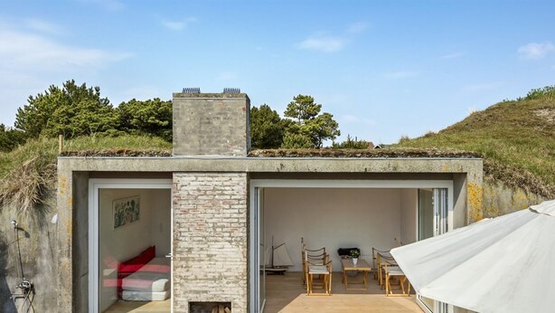A modern, single-story building with a stone facade, a small fireplace, and an outdoor seating area with a table and chairs. - "Dordi" - 300m from the sea by Interhome (Fanø)