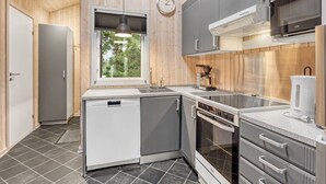 Moderni keittiö, jossa on harmaat kaapit, Bosch-uuni ja kahvinkeitin.