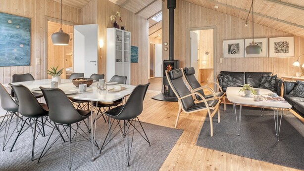 Tilava olohuone, jossa on korkea katto, puuseinät, takka ja modernit huonekalut.