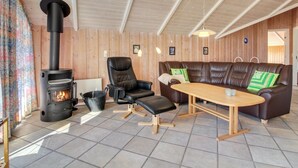 A cozy living room with a wood-burning stove, leather sofa, and a wooden table.