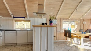A kitchen with a central island, a dining area with a table and chairs, and a window providing natural light.