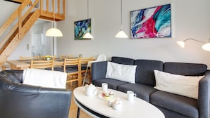 Un salon moderne avec un canapé gris, une table basse ronde et un coin repas doté de meubles en bois.