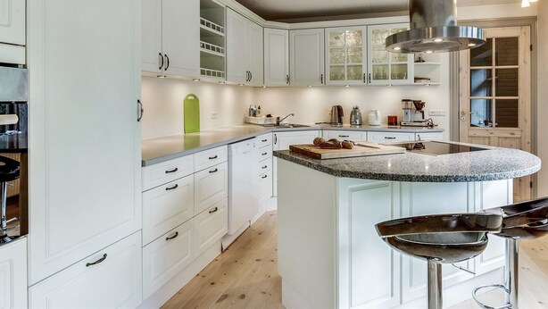 Een moderne keuken met witte kasten, een granieten aanrecht en een roestvrijstalen afzuigkap.
