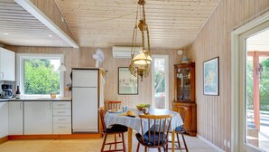 A spacious kitchen with wooden floors, a dining table with chairs, a refrigerator, and a window with a view of greenery. - "Mile" - 260m from the sea by Interhome (Idestrup)