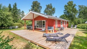A red wooden house with a covered patio, outdoor furniture, and a deck. - "Mile" - 260m from the sea by Interhome (Idestrup)