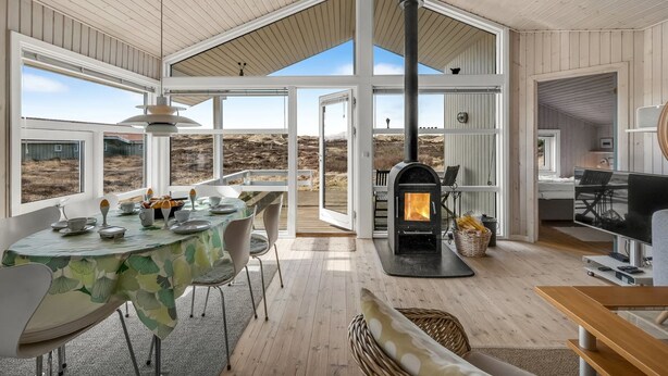 A spacious interior with a high ceiling, a large open dining area, a wood-burning stove, and a view of the outdoors. - "Ferdine" - 1.5km from the sea by Interhome (Fanø)