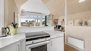A modern kitchen with white cabinetry, a stainless steel range hood, and a large window offering a view of the outdoors. - "Ferdine" - 1.5km from the sea by Interhome (Fanø)