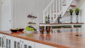 En köksbänk med ett fruktfat i tre våningar, två kopparmuggar och en skål med nötter.
