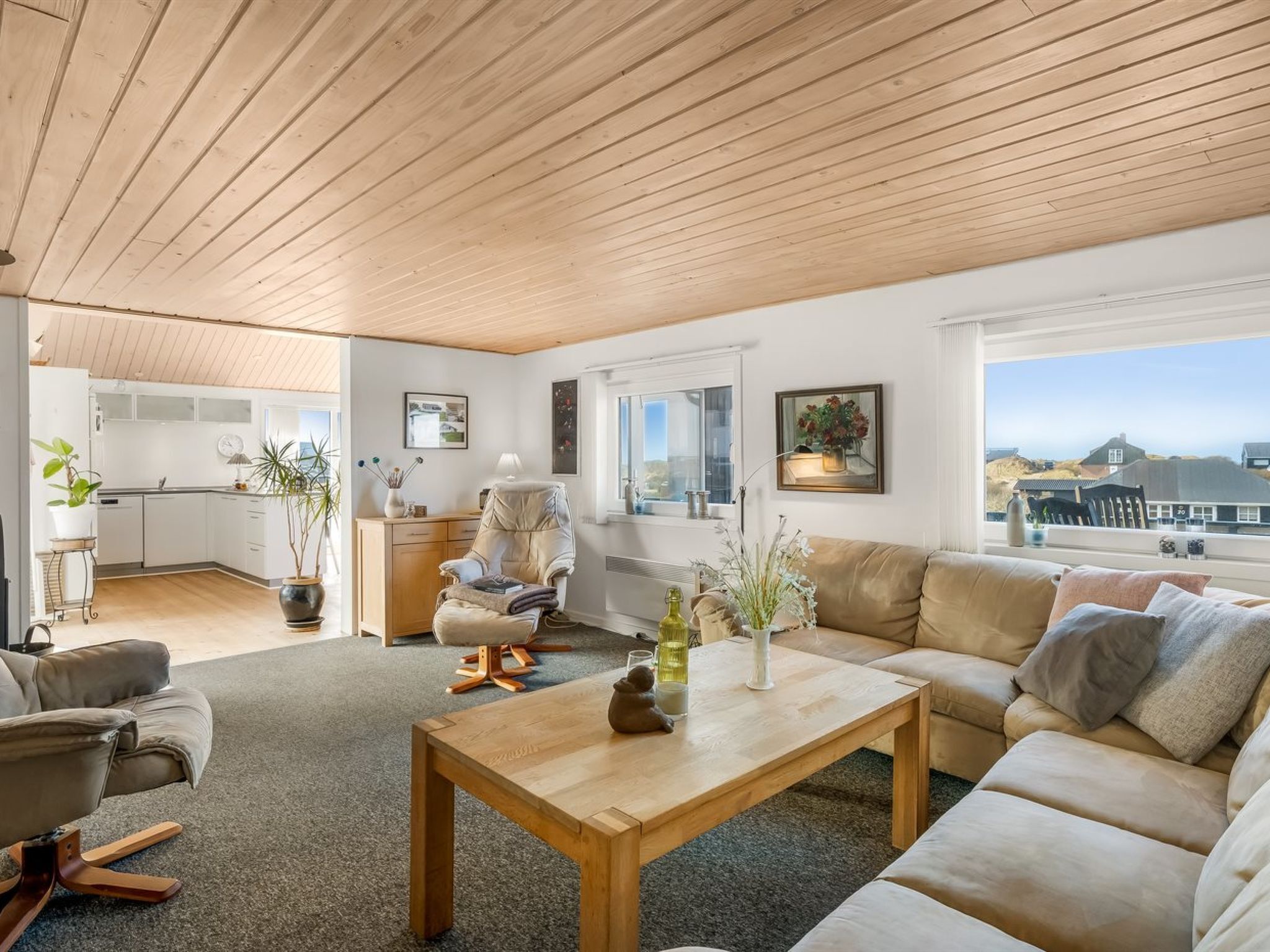 A spacious living area with a wooden ceiling, a sofa, a coffee table, and a view of the outside.