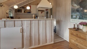 Ein Holzinnenraum mit Küchenzeile, einer Holzkommode und einem Bild an der Wand.