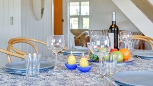 A dining table set with plates, glasses, a bottle of wine, and fruits. - "Inra" - 400m from the sea by Interhome (Fanø)