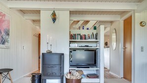 A cozy living room with a wood-burning stove, a flat-screen TV, and a bookshelf filled with books. - "Inra" - 400m from the sea by Interhome (Fanø)