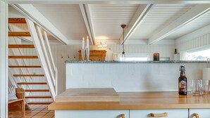 A kitchen with a wooden staircase, white cabinets, and a countertop with a bottle and glasses. - "Inra" - 400m from the sea by Interhome (Fanø)