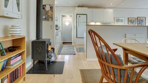Eine gemütliche Küche mit Kaminofen, weißen Schränken und einem Essbereich mit Holztisch und Stühlen.