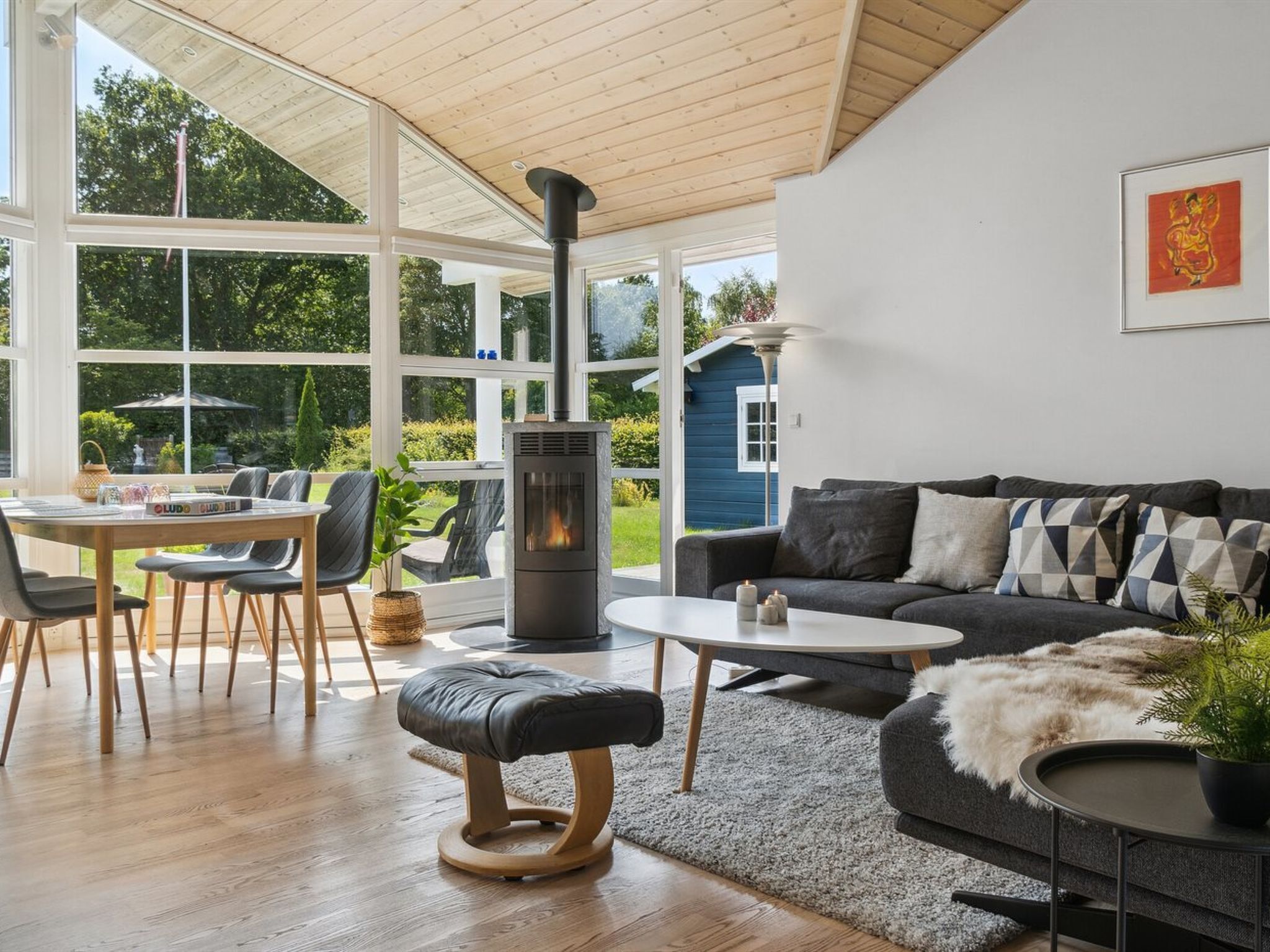 A modern living room with a large window, a fireplace, a sofa, and a dining area.