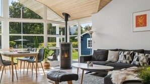 Een moderne woonkamer met een groot raam, een open haard, een bank en een eethoek.
