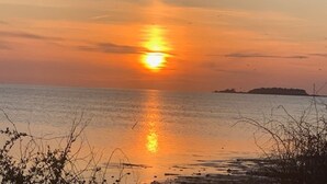 Een zonsondergang boven een rustige zee met een eiland in de verte.