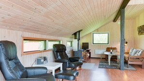 Un intérieur de chalet chaleureux avec des murs en bois, un coin repas et des sièges en cuir.