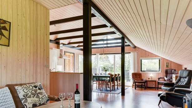 Un loft spacieux avec de hauts plafonds, des murs en bois, un coin repas et un espace salon confortable agrémenté d’une cheminée.