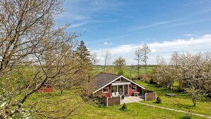 Une cabane en bois rouge avec un toit en pente, une véranda et un petit espace patio.