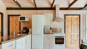 Une cuisine compacte avec des appareils électroménagers blancs, un lambris en bois et un îlot central.