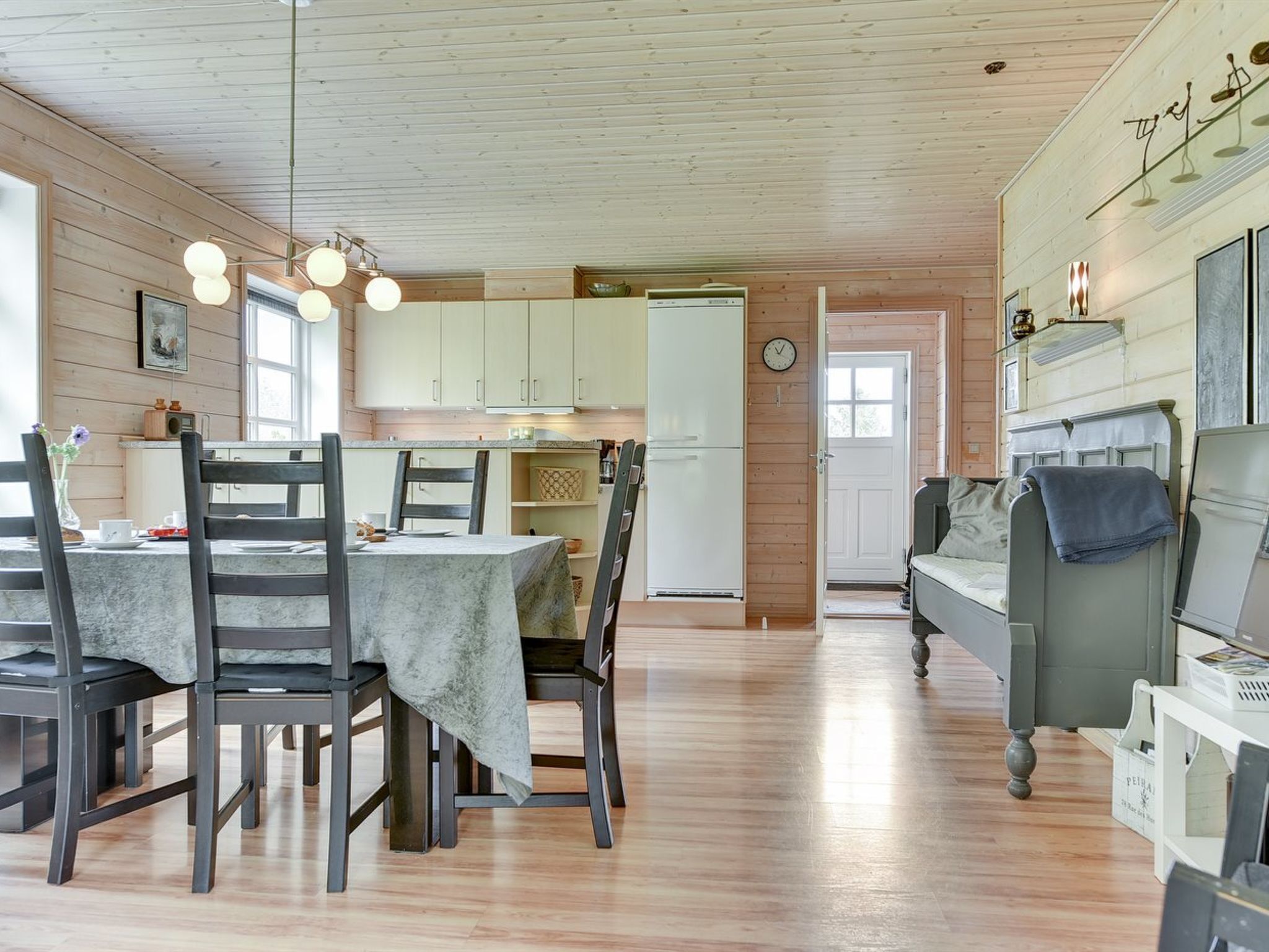 Une pièce chaleureuse et bien éclairée, avec une table à manger dressée pour quatre personnes, un canapé et un lit.