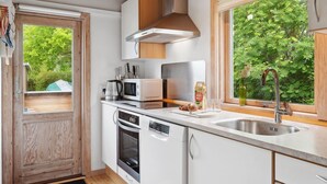Een moderne keuken met witte kasten, roestvrijstalen apparatuur en een groot raam met uitzicht op groen.
