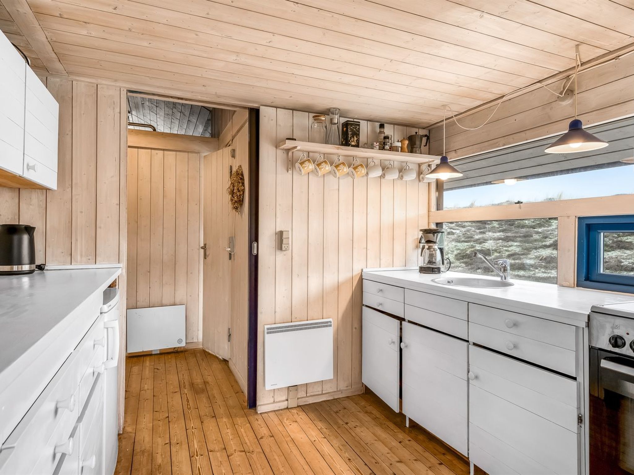 A modern kitchen with wooden walls, a window, and a built-in oven.
