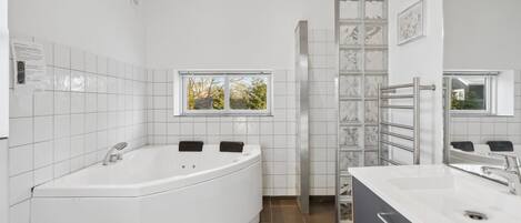 A modern bathroom with a freestanding bathtub, a vanity with a mirror, and a window providing natural light.