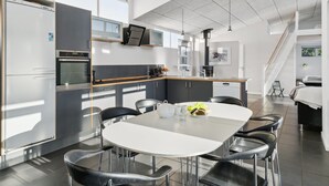 A modern kitchen with a dining area, featuring stainless steel appliances, a large island, and a staircase leading to an upper level. - "Bjerne" - 200m from the sea by Interhome (Rødvig Stevns)