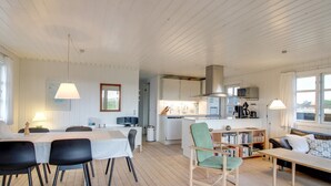 A spacious living area with a dining table, chairs, a sofa, and a kitchen in the background. - "Eikka" - 600m from the sea by Interhome (Fanø)