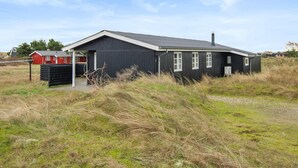 A black building with a sloped roof and white trim, surrounded by grassy fields. - "Eikka" - 600m from the sea by Interhome (Fanø)