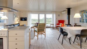 A modern kitchen with a built-in stove, wooden cabinets, and a dining area with a table and chairs. - "Eikka" - 600m from the sea by Interhome (Fanø)