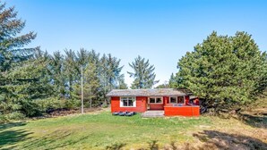 A red cabin with a small porch, surrounded by a grassy area and dense trees. - "Byrge" - 2km from the sea by Interhome (Fanø)