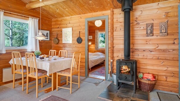 A wooden cabin interior with a dining area, a bed, a fireplace, and a view of the outdoors. - "Byrge" - 2km from the sea by Interhome (Fanø)