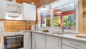 A compact kitchen with a stove, sink, and white cabinets, featuring a window with a view of trees. - "Byrge" - 2km from the sea by Interhome (Fanø)
