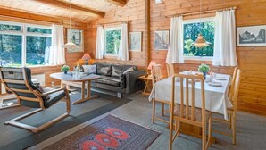 A wooden cabin interior with a sofa, dining table, chairs, and artwork on the walls. - "Byrge" - 2km from the sea by Interhome (Fanø)