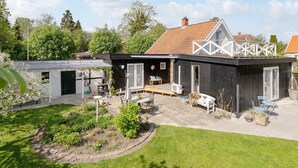 Ein modernes Haus mit Terrasse, einer kleinen Holzterrasse und einem Garten.