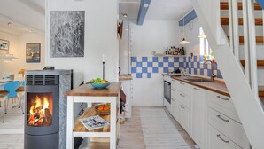 Eine moderne Küche mit Kaminofen, weißen Schränken und einer blau-weißen Karosboden-Spritzwand.