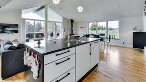 A modern kitchen with a large island, white cabinetry, and pendant lighting.
