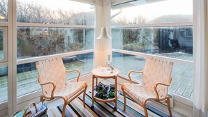 A sunlit room with large windows, two wicker chairs, a small table, and a lamp. - "Fenneke" - 50m from the sea by Interhome (Blokhus)