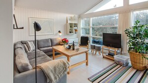 A modern living room with a grey sofa, a coffee table, a TV, and a large window. - "Fenneke" - 50m from the sea by Interhome (Blokhus)
