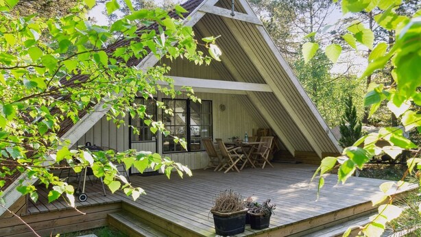 Une terrasse en bois avec des meubles d’extérieur, une petite table et des plantes en pot.