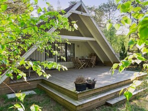 A wooden deck with outdoor furniture, a small table, and potted plants. - "Jörn" - 800m from the sea by Interhome (Vig)