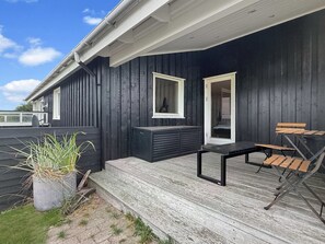 A dark wooden deck with a bench and a table, a potted plant, and a door leading to an interior space. - "Steffenie" - 400m from the sea by Interhome (Løkken)