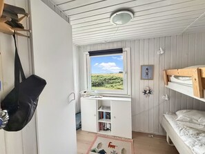 A compact room with a bunk bed, a desk with books, a hanging bag, and a window with a view of greenery. - "Steffenie" - 400m from the sea by Interhome (Løkken)
